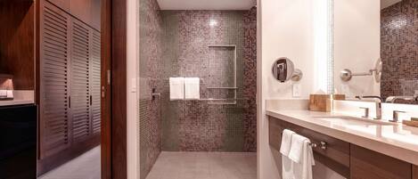 Une salle de bain moderne avec une douche à l’italienne, des meubles en bois et un grand miroir.