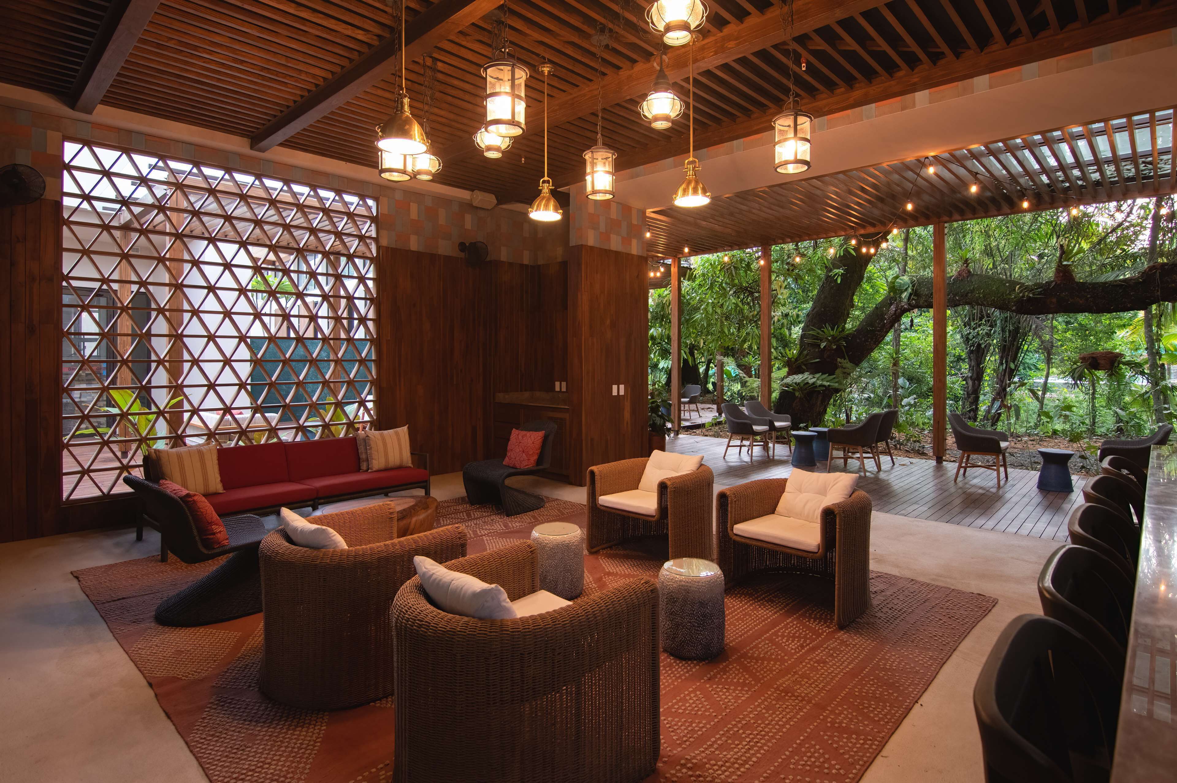 A spacious indoor area with wicker furniture, a red sofa, and a large wooden partition with a geometric pattern.
