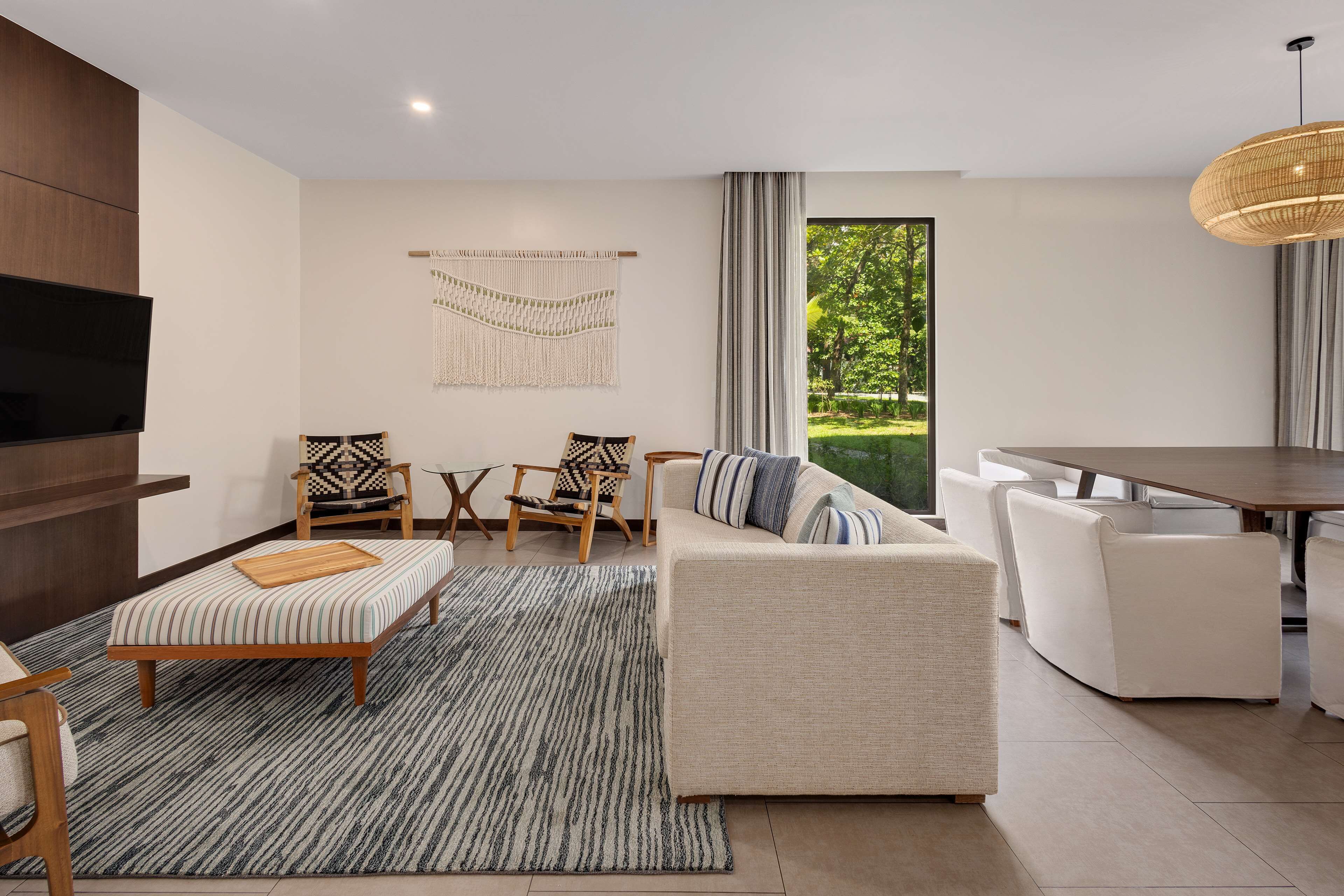 A modern living room with a sofa, chairs, a TV, and a dining area with a table and chairs.