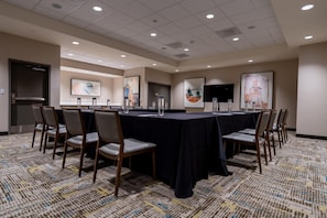 A conference room with a long table, chairs, and artwork on the walls.