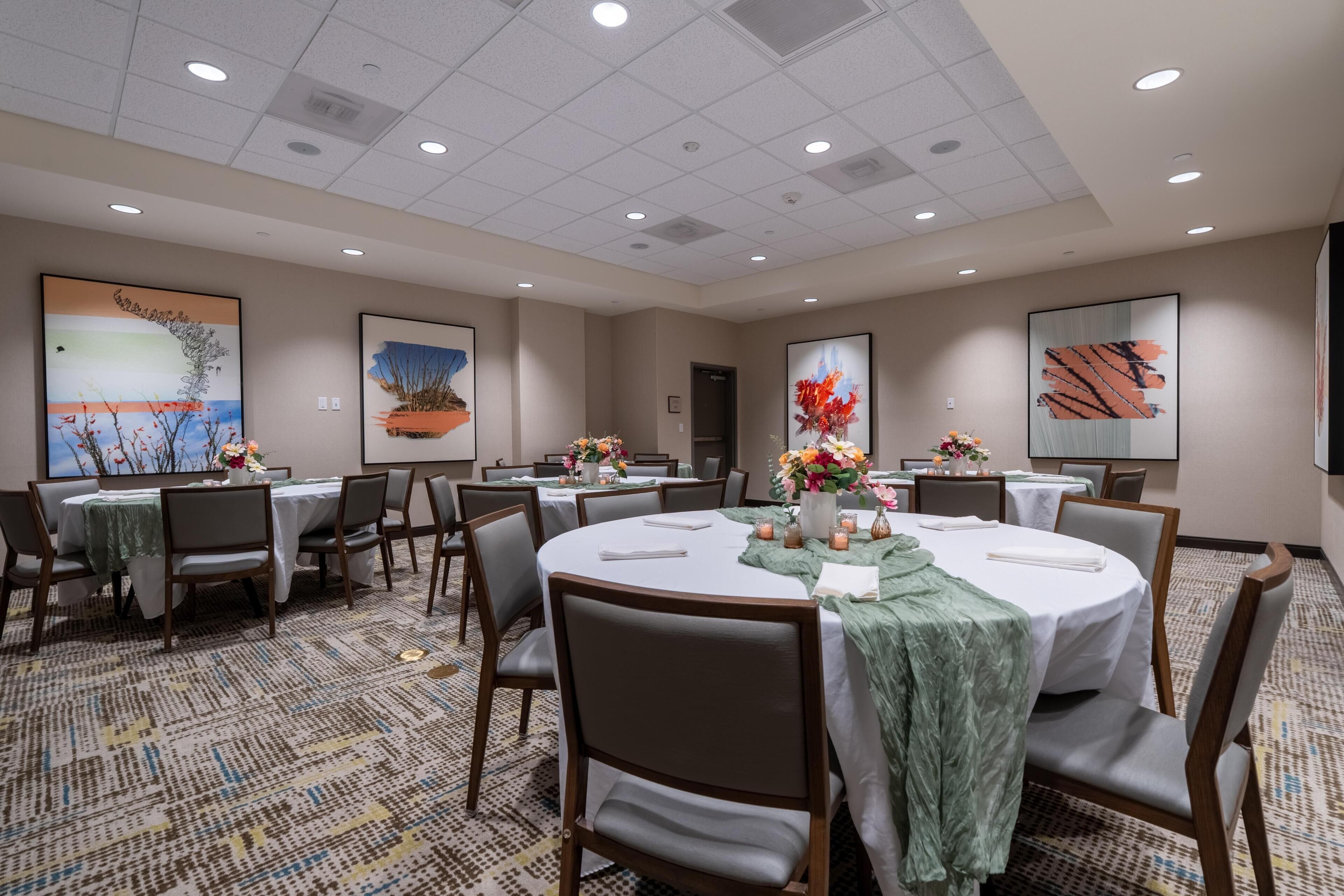 A conference room with round tables, chairs, and floral centerpieces.