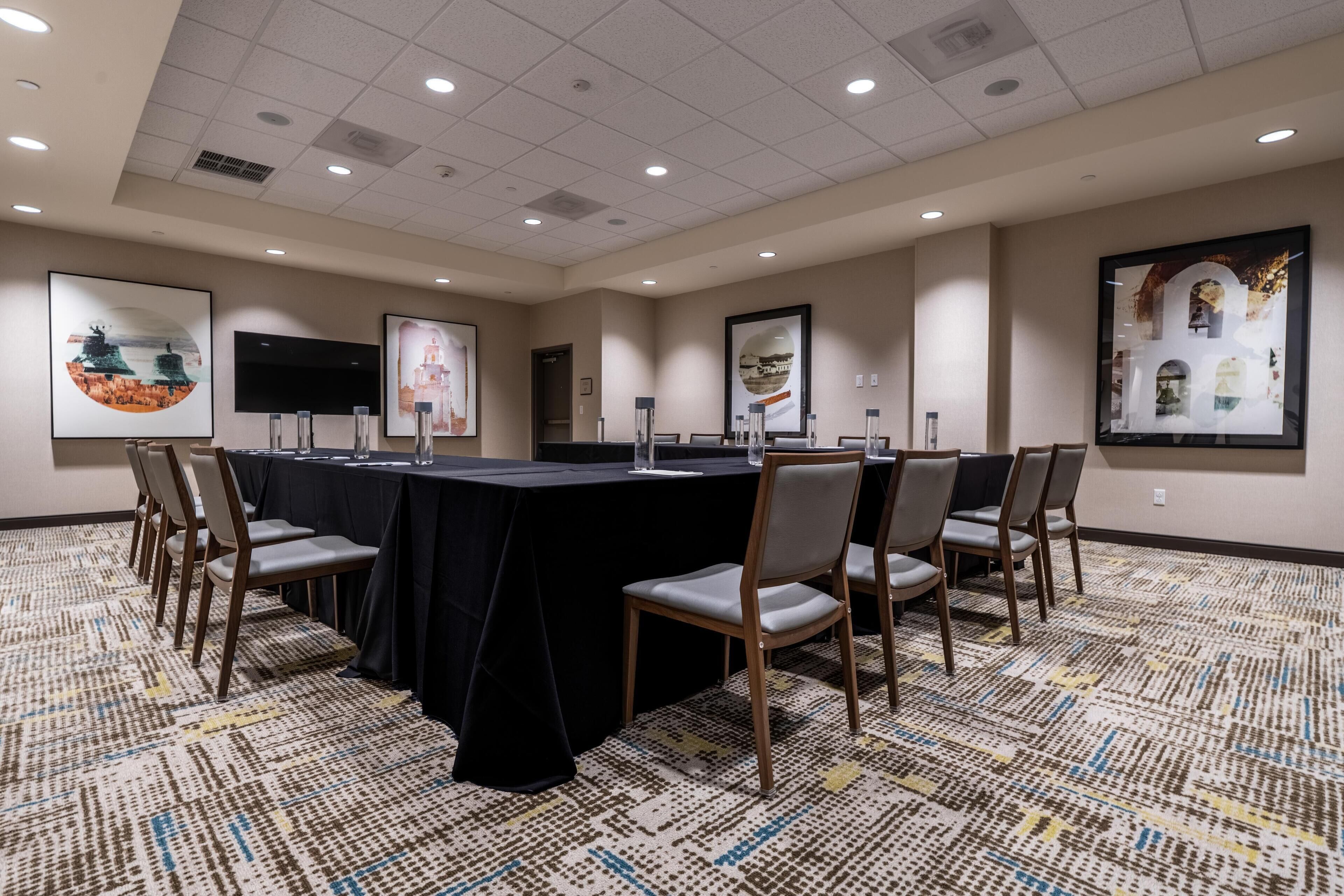 A conference room with a long table, chairs, and framed artwork on the walls.