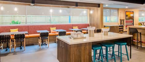 Un restaurante moderno con una isla central, taburetes de bar y un área de estar con bancos y mesas.