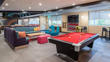 Un'area lounge moderna con tavolino da biliardo, comodi posti a sedere e un angolo bar.