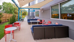 Eine Terrasse im Freien mit einer blauen Sofagarnitur, roten Stühlen und einem weißen Tisch.
