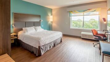 Habitación de hotel con una cama grande, un escritorio, una silla, un ventanal con vistas y un ventilador de techo.