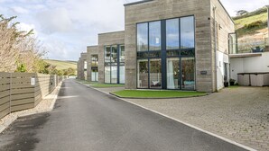 A modern building with large windows and a paved driveway. - Close To The Beach,Wi-Fi, Parking (Challaborough)