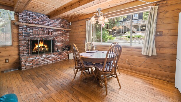 A cozy cabin interior with a brick fireplace, wooden dining table, and chairs.