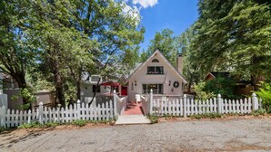 A two-story house with a white picket fence, a red door, and a front porch.
