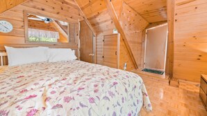 A wooden cabin bedroom with a bed, a window, and a door.
