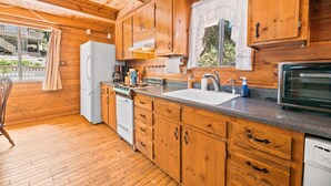 A wooden cabin kitchen with a refrigerator, stove, sink, and dishwasher.