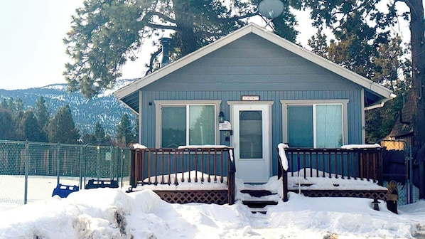 Une petite cabane avec une véranda, une porte et une boîte aux lettres.
