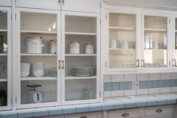 A kitchen with white cabinets, a scale, and a tiled backsplash.