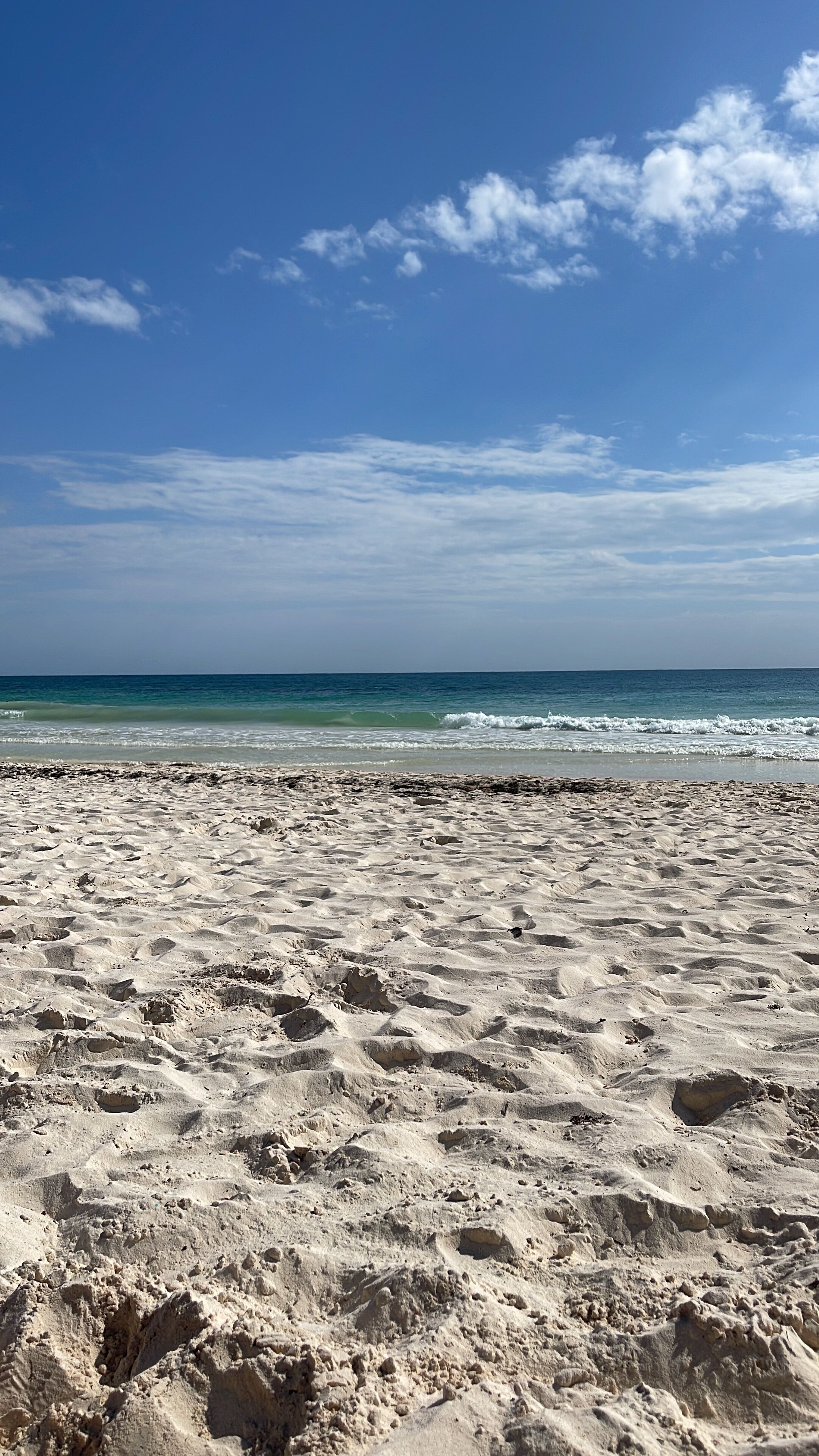 A sandy beach with waves in the background.