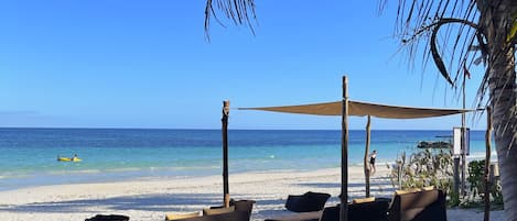 En la playa, arena blanca, sillas reclinables de playa