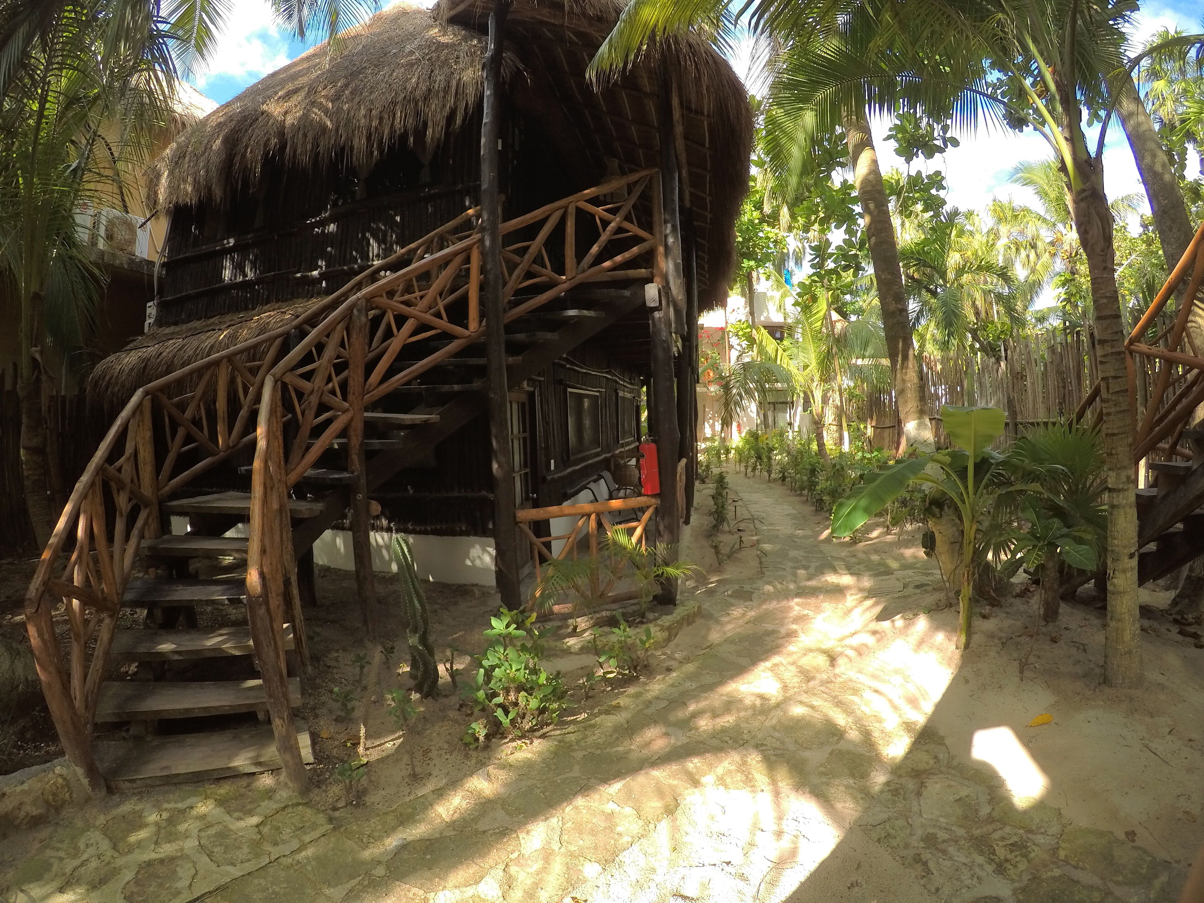 A rustic wooden structure with a thatched roof, a wooden staircase, and a small seating area.