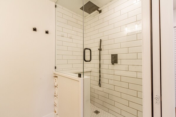 A modern bathroom with white subway tiles, a glass shower enclosure, and a visible showerhead.