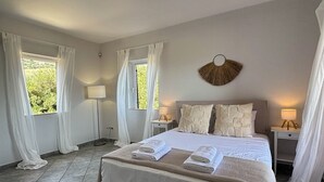 Een goed verlichte slaapkamer met een groot bed, twee nachtkastjes en een decoratief object aan de muur.
