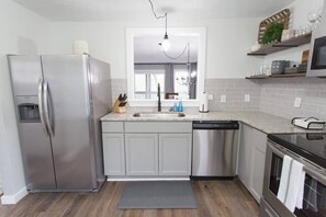A modern kitchen with stainless steel appliances, a gray countertop, and a large window.