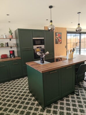 Una cocina moderna con armarios verdes, una isla de madera y piso con diseño.
