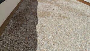 Un patio con cerca de madera, camino de grava y un edificio con ventanas.