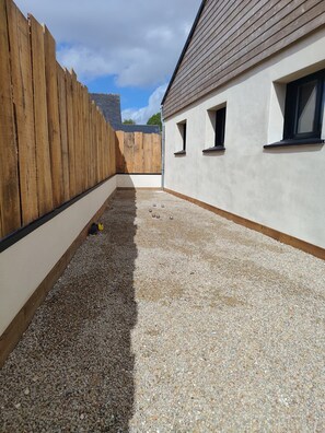A courtyard with a wooden fence, a gravel path, and a building with windows. - Wellness Villa for 12 Guests • Indoor pool, sauna, billiards, pétanque (Plouvorn)