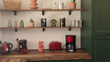Una cocina con estantes de madera, cafetera, tostadora y hervidor.