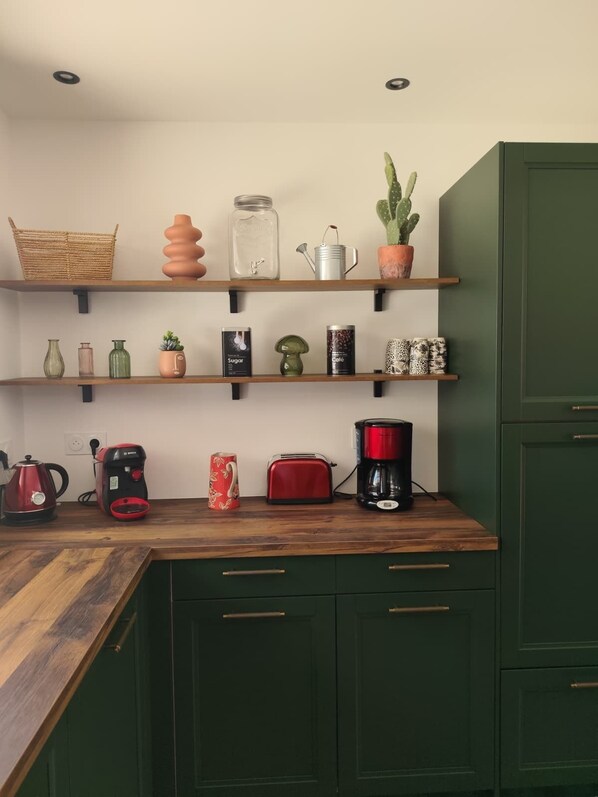 Une cuisine avec des étagères en bois, une machine à café, un grille-pain et une bouilloire.