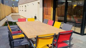 Un espacio moderno al aire libre con una larga mesa de madera y sillas de colores.