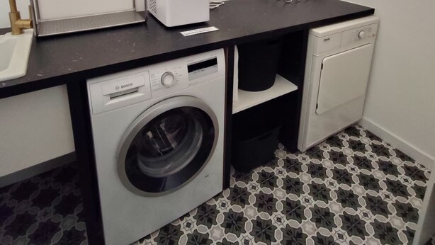 Un lavadero pequeño con una lavadora Bosch, una secadora y un lavamanos.