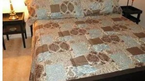 A bed with a patterned bedspread, a wooden headboard, a bedside table with a lamp, and a nightstand with a lamp. - Two bedroom apartment with lots of light (Atlanta)
