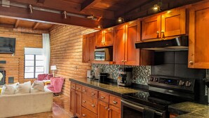 Une cuisine avec des meubles de rangement en bois, un pare-feu en carrelage et un four encastré.