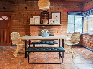A cozy dining area with a brick wall, a round table, and wicker chairs.