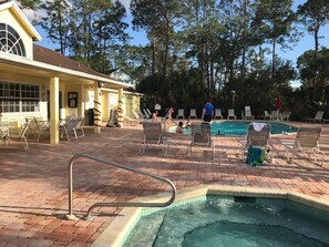 Área de piscina com espreguiçadeiras e um edifício com uma grande janela.