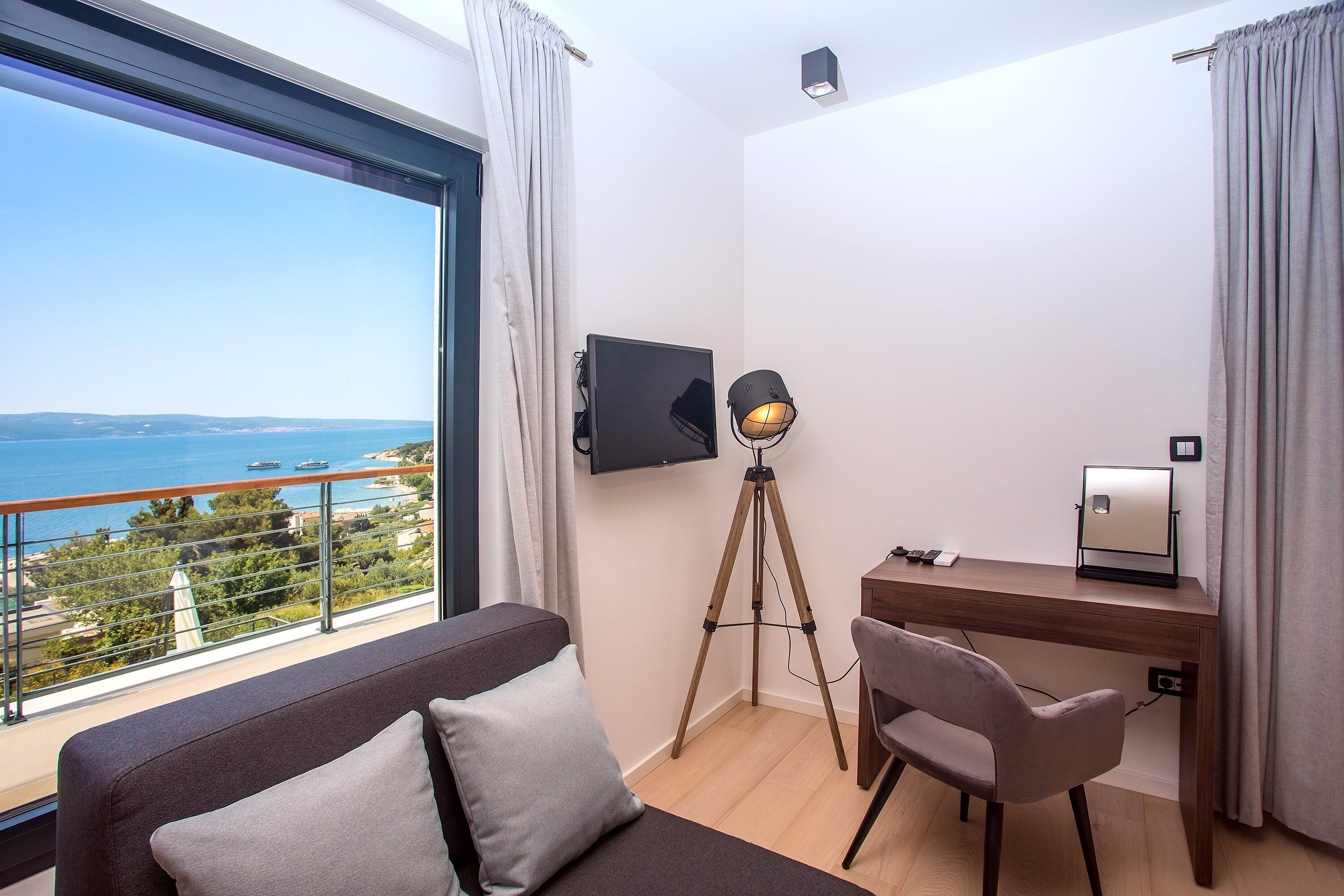 Een kamer met een groot raam, een bureau, een stoel en een bed.