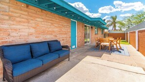 Un patio con un sofá azul, una mesa de madera y sillas.