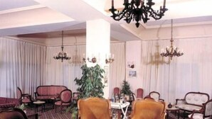 A room with a patterned carpet, multiple armchairs, a table, and a chandelier. - Hotel Le Crillon (Broumana)