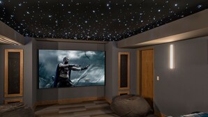 Une salle de cinéma privée avec un plafond étoilé, un grand écran et des sièges bleus.