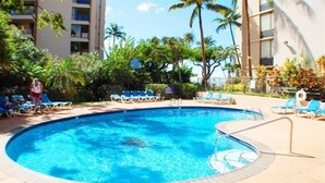 Uma piscina com espreguiçadeiras e palmeiras.