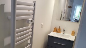 A bathroom with a white radiator, a mirror, and a sink with wooden storage.