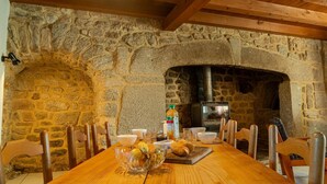 A stone-walled dining area with a long wooden table set for a meal.