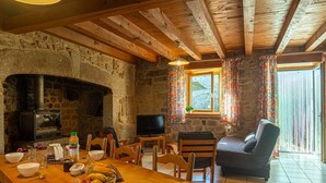 A rustic stone interior with a fireplace, wooden dining table, and a cozy seating area.
