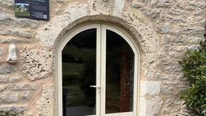 A stone building with a glass door and a poster on the wall. - Gîte "La Prairie" - LA CANOURGUE (LA CANOURGUE)