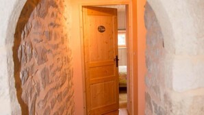 A stone-walled hallway leading to a wooden door with a sign above it. - Gîte "La Prairie" - LA CANOURGUE (LA CANOURGUE)