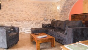 A cozy living room with a stone wall, a wooden coffee table, and two armchairs. - Gîte "La Prairie" - LA CANOURGUE (LA CANOURGUE)