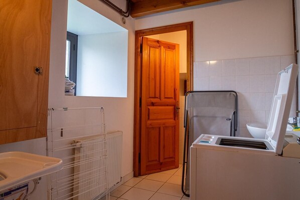 A compact kitchen with a wooden door, a white radiator, a drying rack, and a white sink.