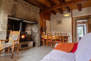 Una habitación acogedora con chimenea de piedra, mobiliario de madera y suelo de baldosas.