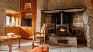 A cozy room with a stone fireplace, wooden furniture, and a television.