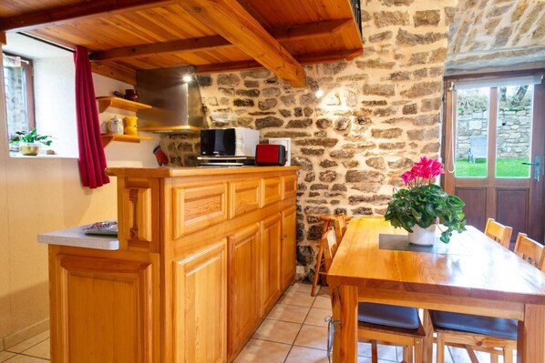 Eine Küche mit Holzschränken, einer Steinwand, einem Holztisch und einem Blumentopf.