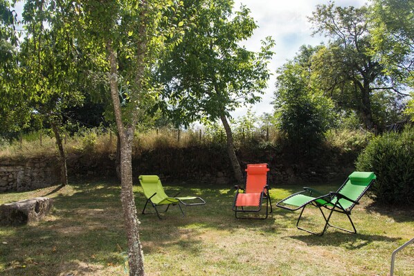 An outdoor seating area with three lawn chairs and a stone wall in the background.